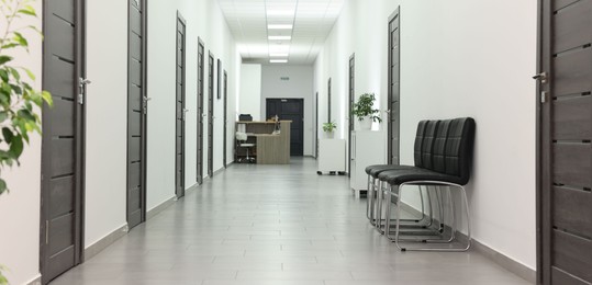 Empty hospital corridor with chairs and doors