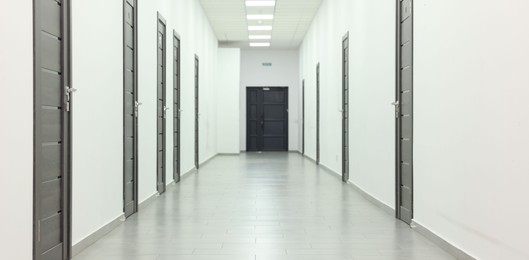 View of empty hospital corridor with wooden doors