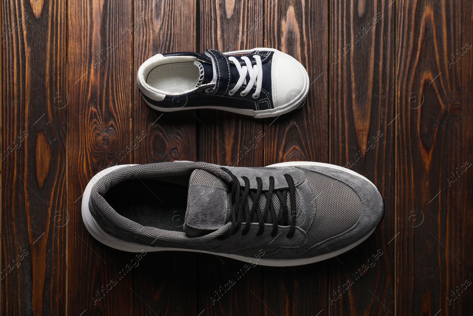 Photo of Big and small shoes on wooden table, top view