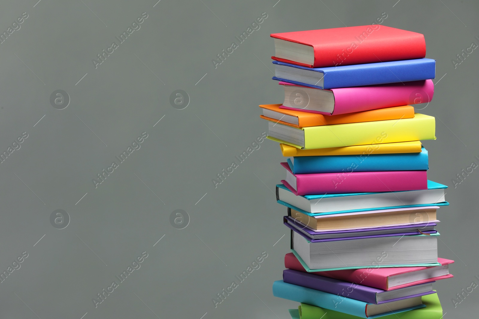 Photo of Stack of colorful books on light grey background, space for text