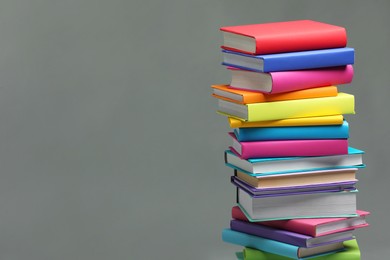 Photo of Stack of colorful books on light grey background, space for text