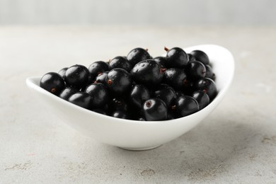 Fresh ripe black currants in bowl on light table