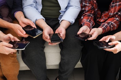 Photo of People holding smartphones with blank screens indoors, closeup