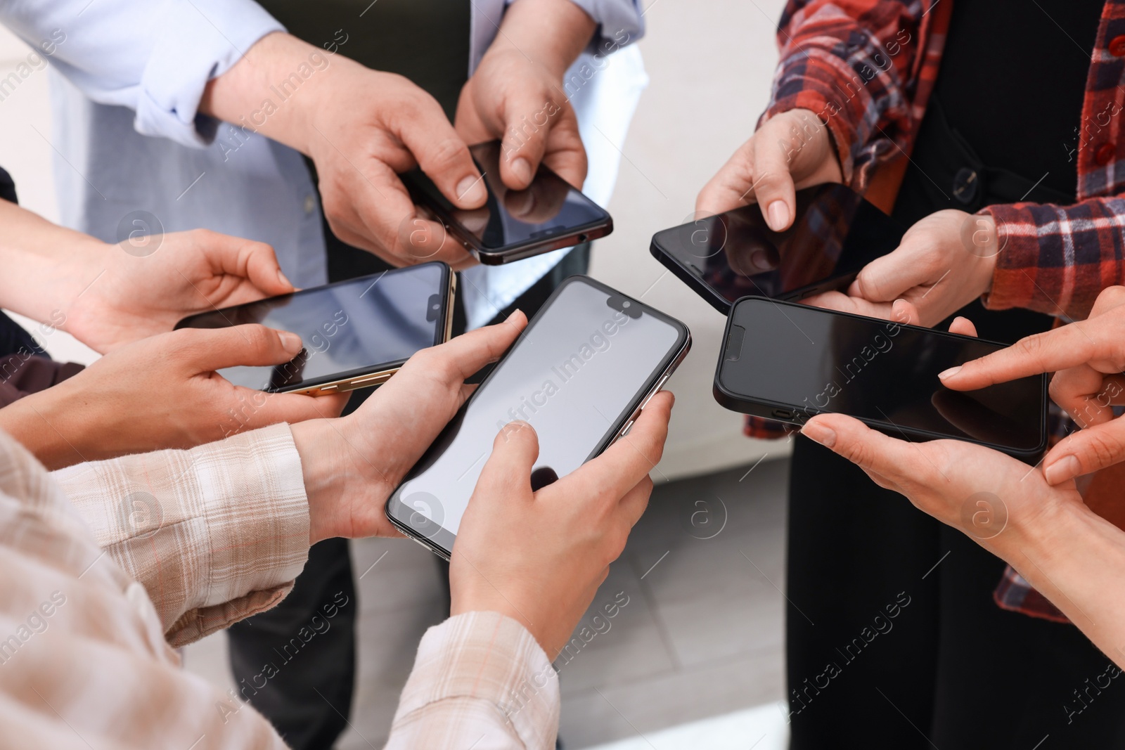 Photo of People holding smartphones with blank screens indoors, closeup