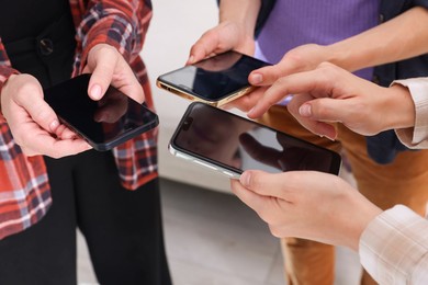 Photo of People holding smartphones with blank screens indoors, closeup