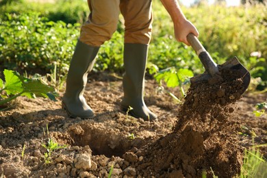 Farmer digging soil with shovel on sunny day, closeup