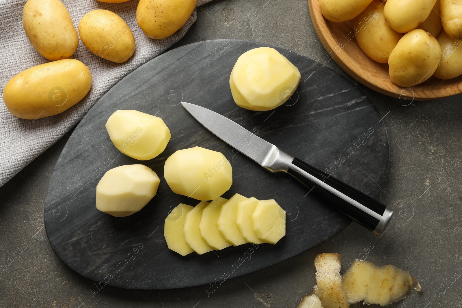 Photo of Fresh raw potatoes and knife on grey table, top view