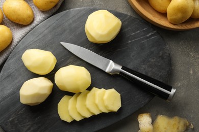 Photo of Fresh raw potatoes and knife on grey table, top view