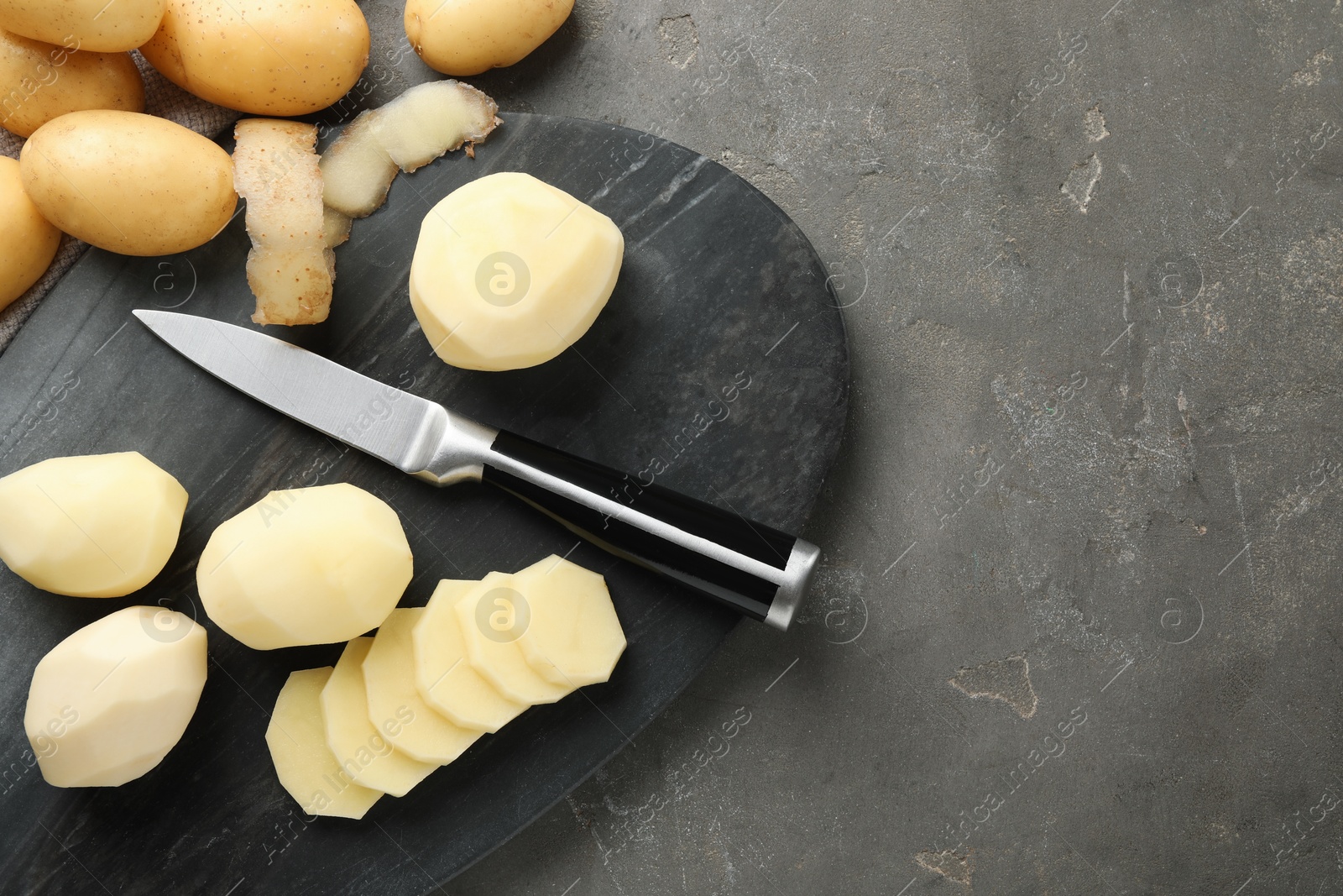 Photo of Fresh raw potatoes and knife on grey table, top view. Space for text