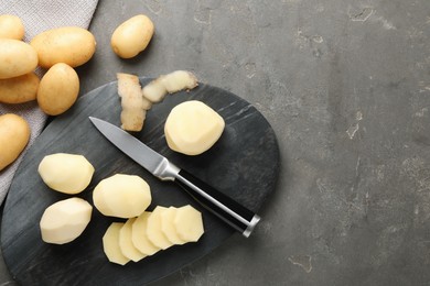 Fresh raw potatoes and knife on grey table, top view. Space for text