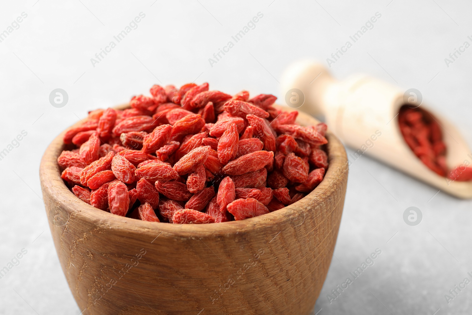 Photo of Dried goji berries in bowl on light grey table, closeup