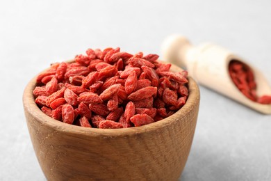 Photo of Dried goji berries in bowl on light grey table, closeup