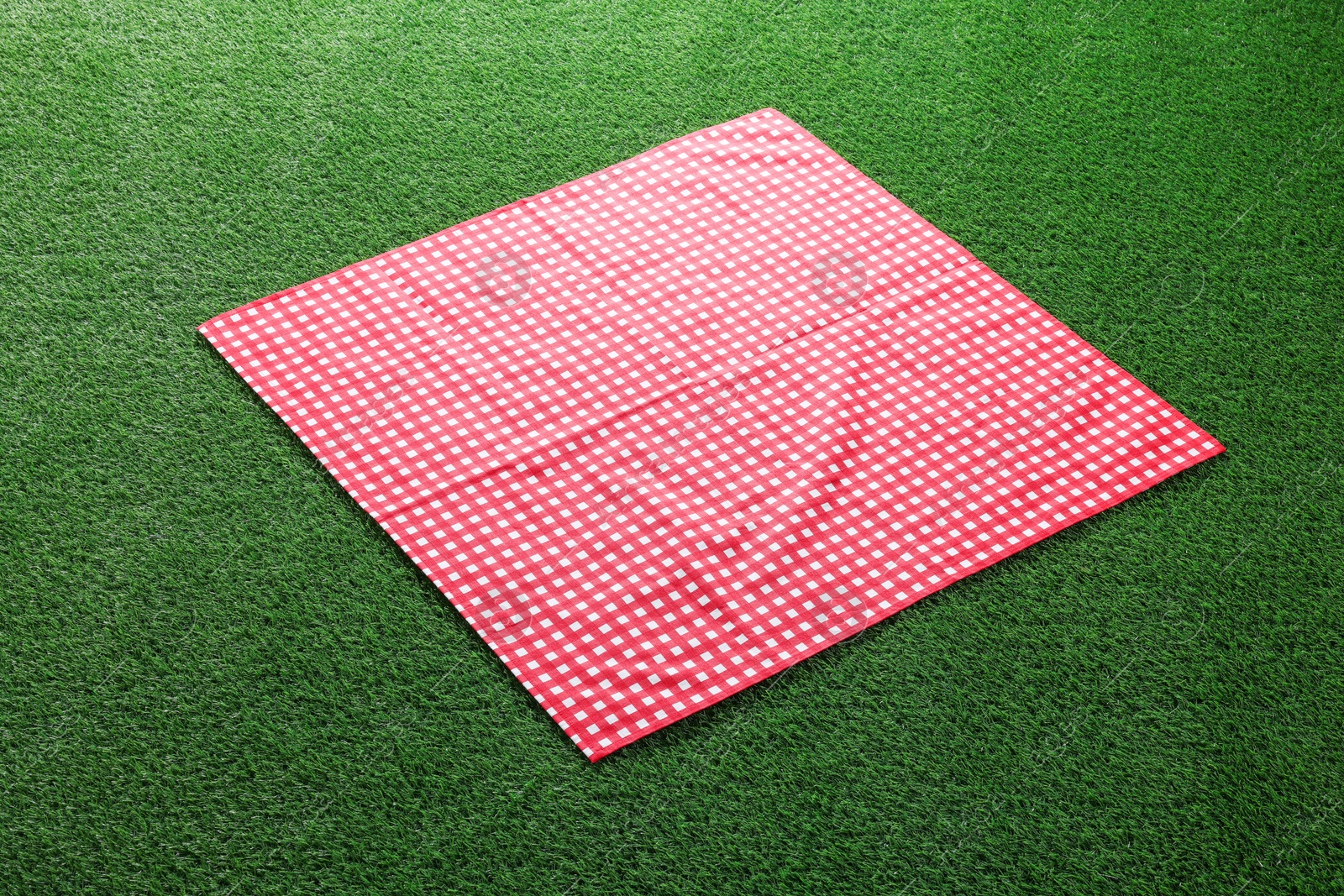 Photo of Red checkered picnic tablecloth on green grass
