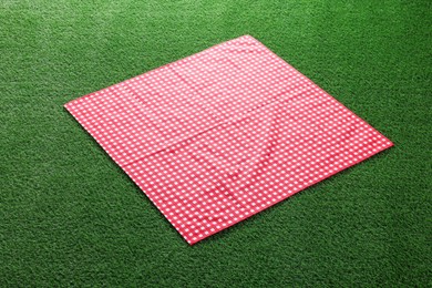 Photo of Red checkered picnic tablecloth on green grass