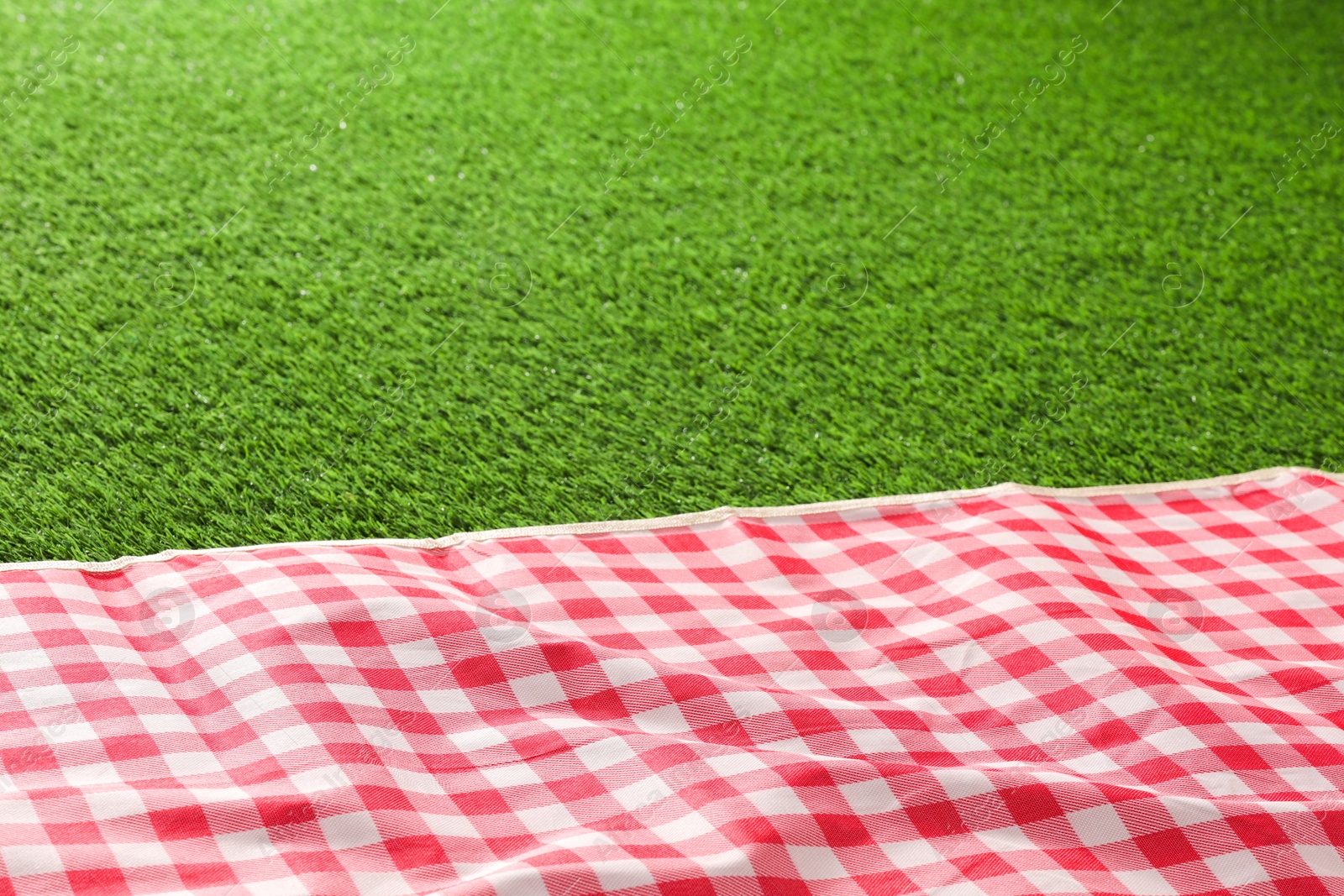 Checkered picnic tablecloth on green grass, closeup. Space for text Photo of Checkered picnic tablecloth on green grass, closeup. Space for text