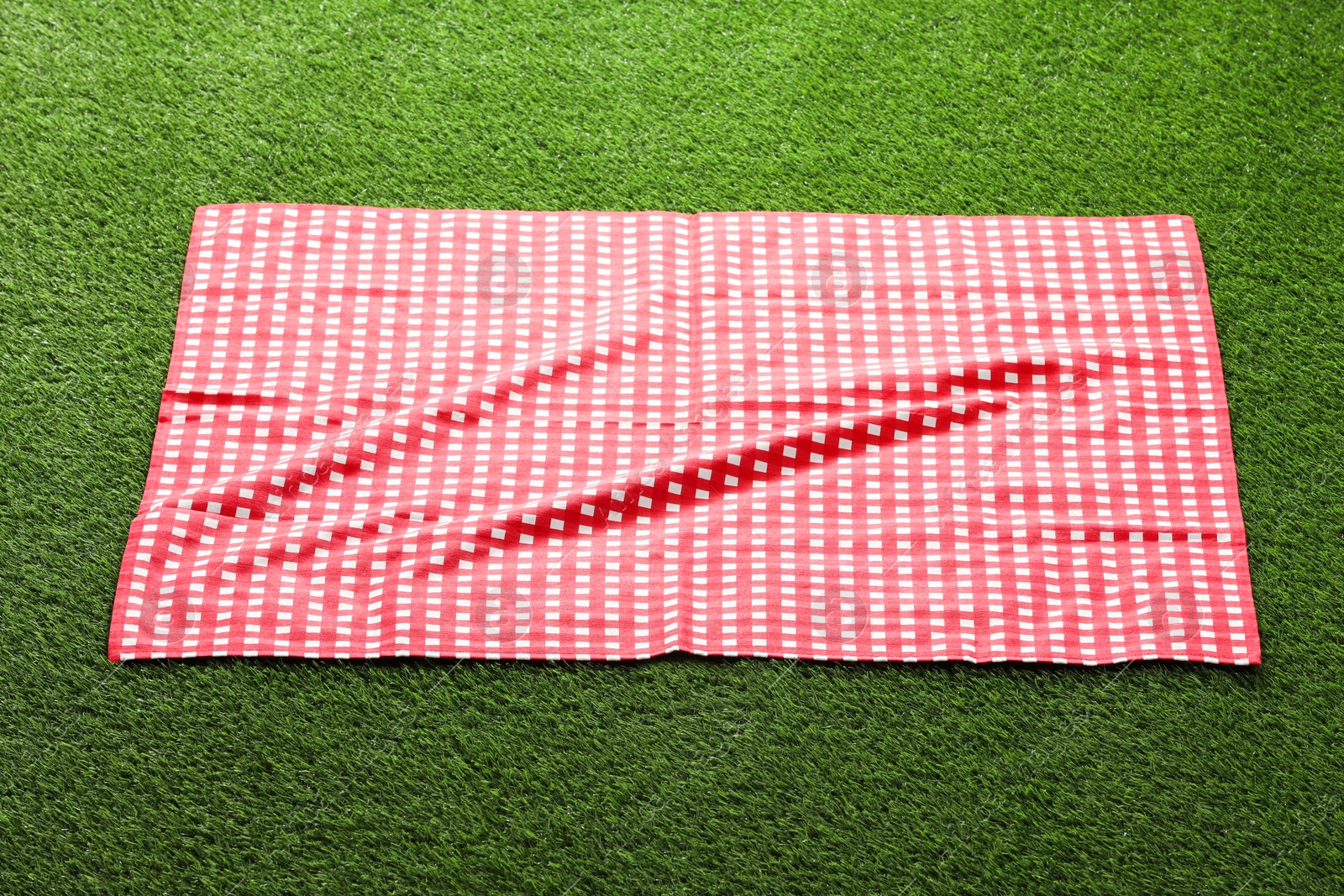 Checkered picnic tablecloth on green grass, closeup Photo of Checkered picnic tablecloth on green grass, closeup