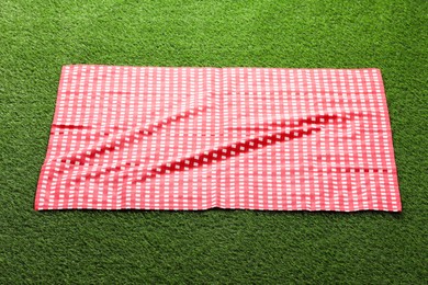 Photo of Checkered picnic tablecloth on green grass, closeup