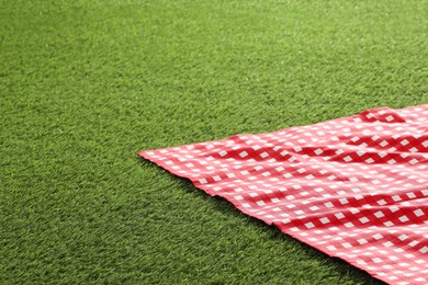 Photo of Checkered picnic tablecloth on green grass. Space for text