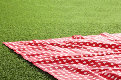 Photo of Checkered picnic tablecloth on green grass, closeup