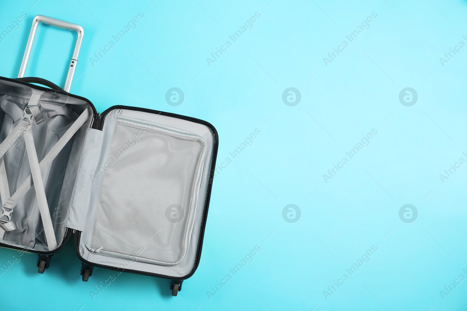 Photo of Open empty suitcase on light blue background, top view. Space for text