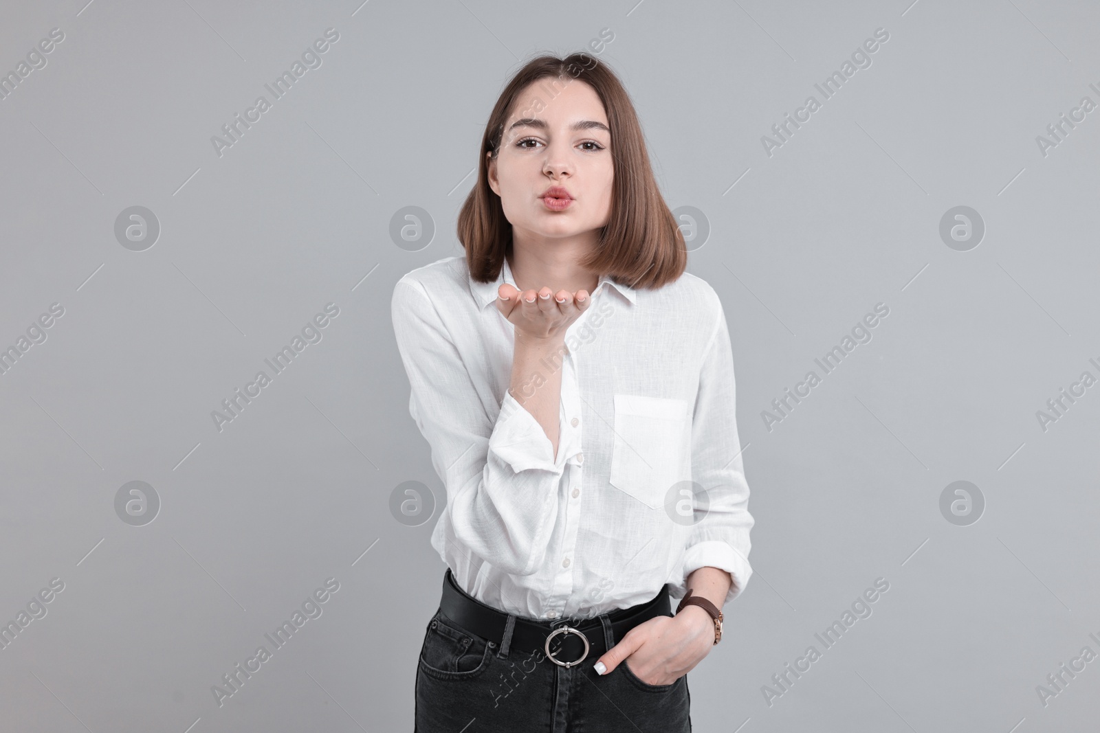 Photo of Beautiful teenage girl blowing kiss on gray background