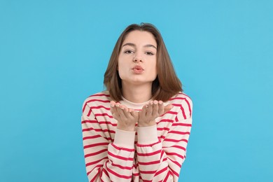 Photo of Beautiful teenage girl blowing kiss on light blue background