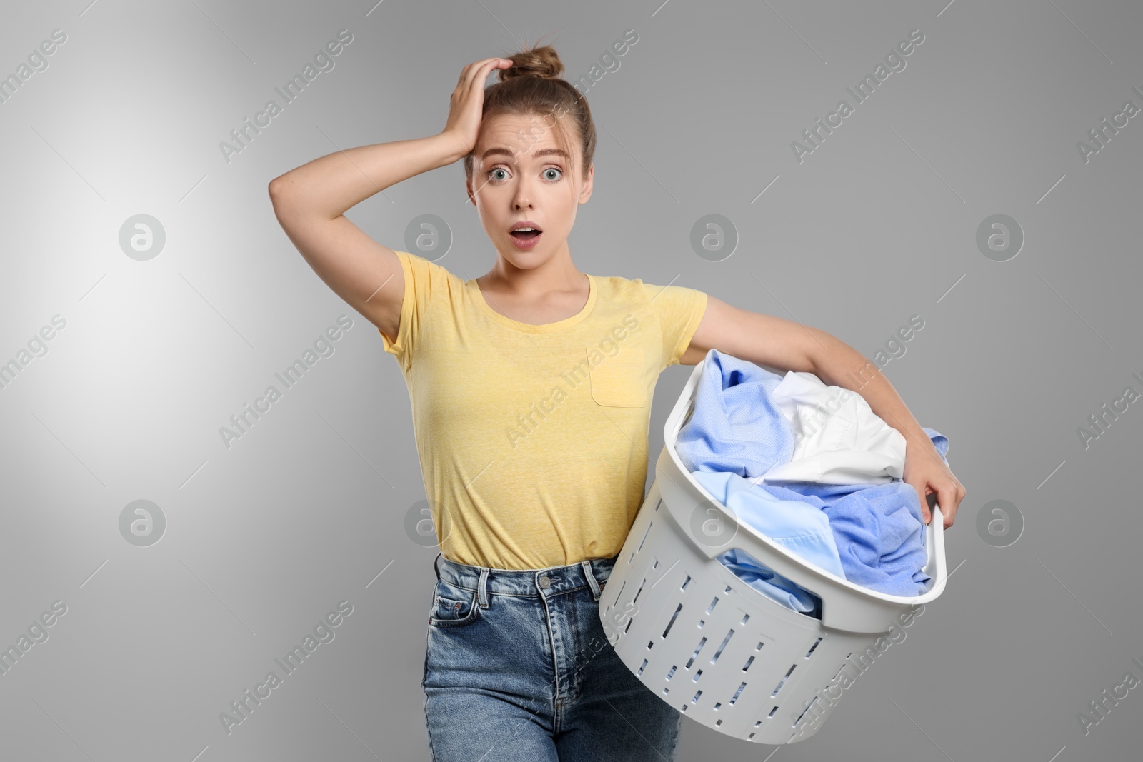 Photo of Emotional housewife with basket full of laundry on grey background