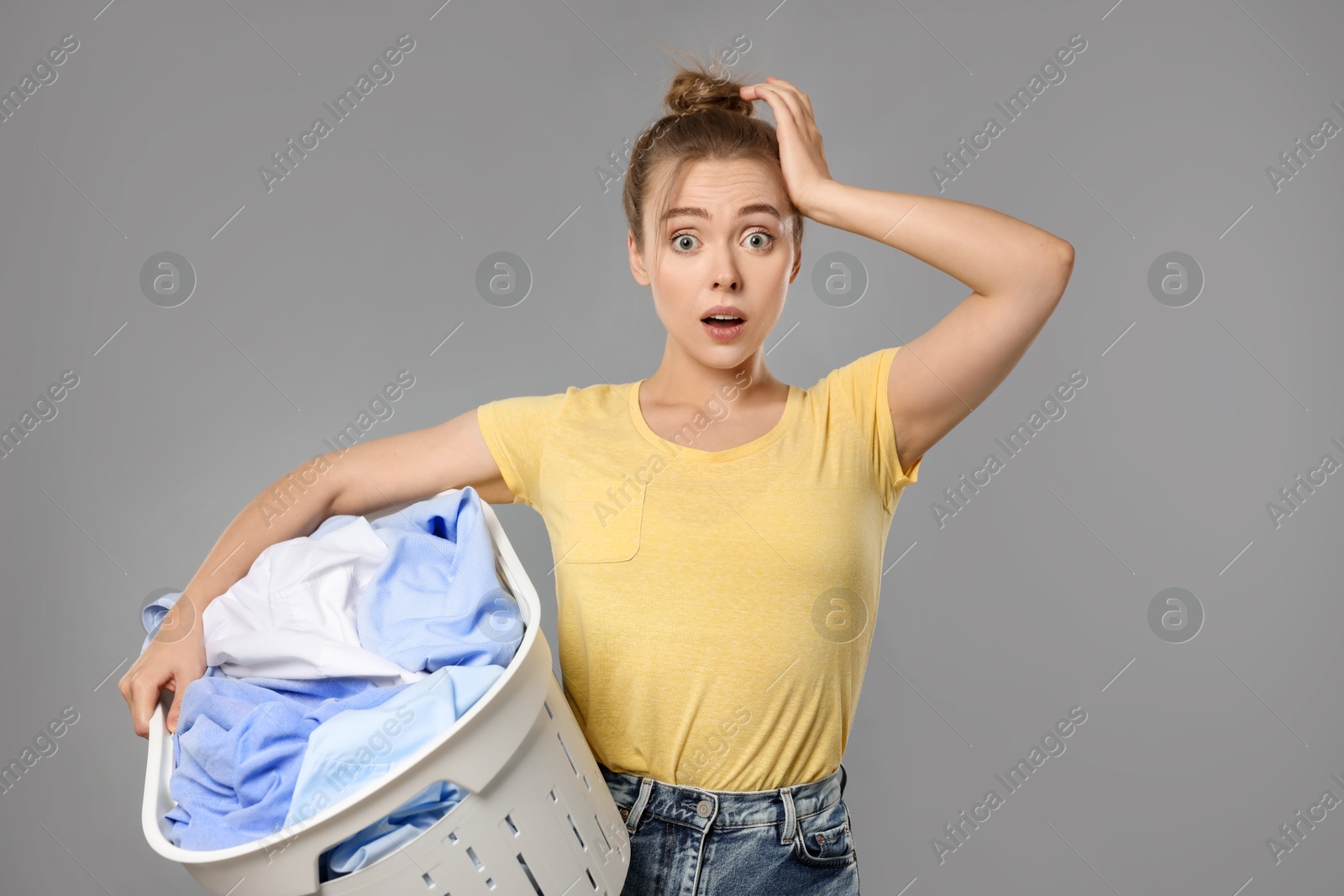 Photo of Emotional housewife with basket full of laundry on grey background