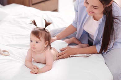 Photo of Mother changing her baby's diaper on bed