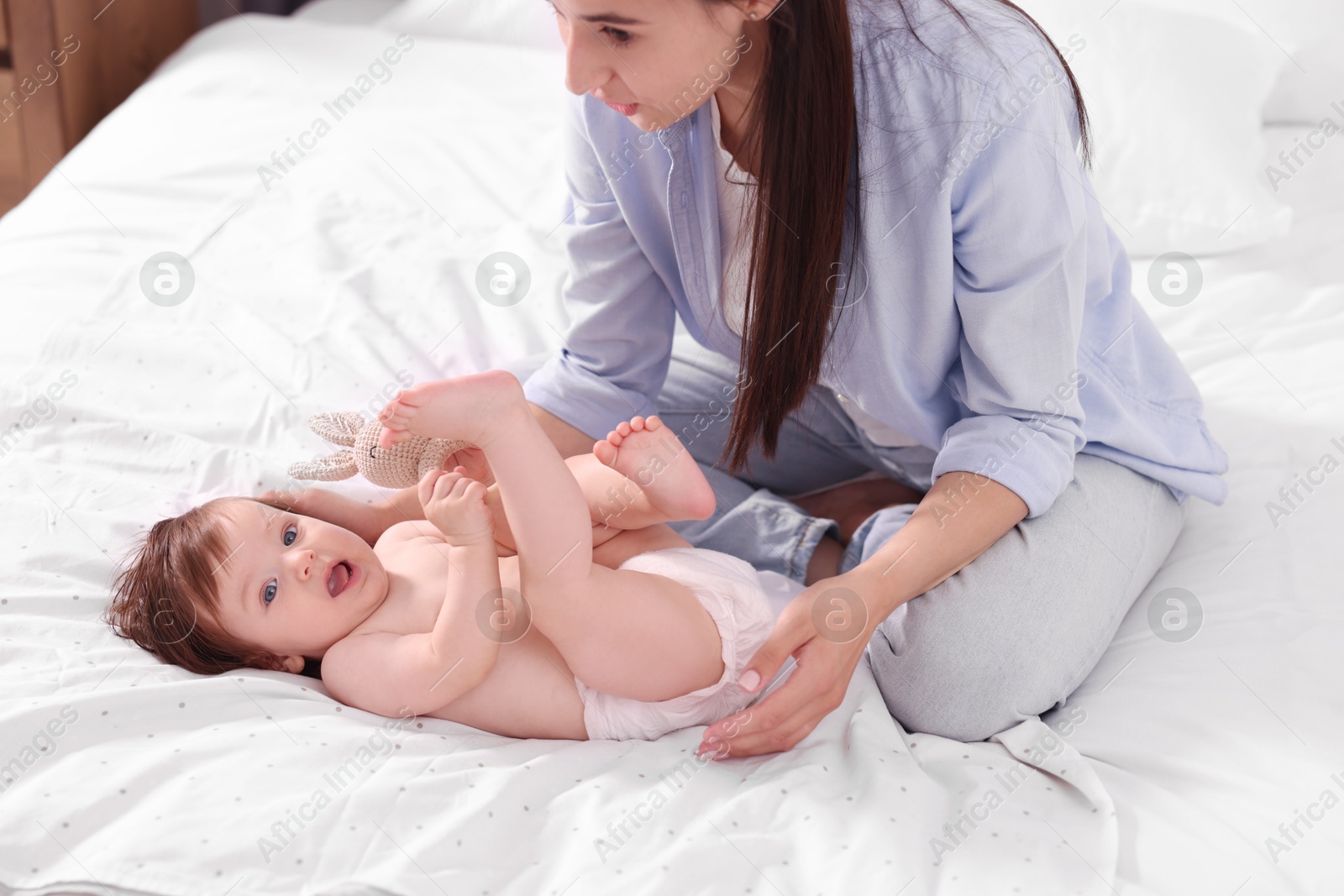 Photo of Mother changing her baby's diaper on bed