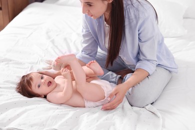 Photo of Mother changing her baby's diaper on bed