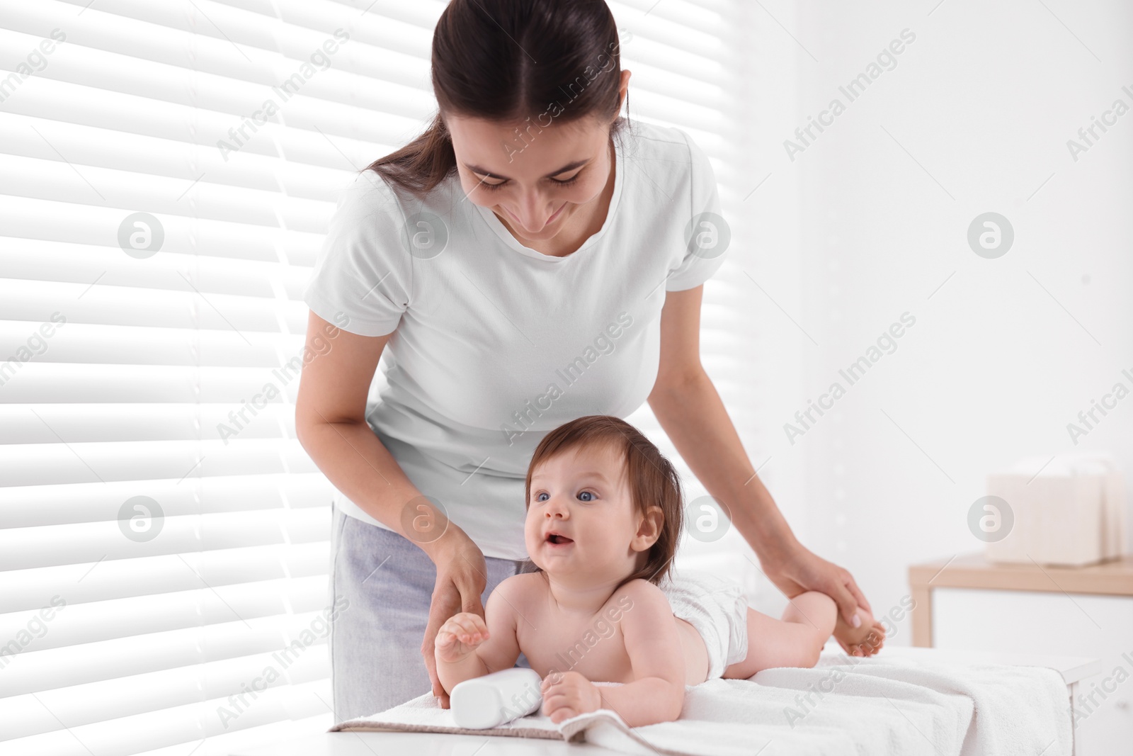 Photo of Mother changing her baby's diaper on table at home