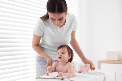 Photo of Mother changing her baby's diaper on table at home