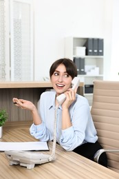 Professional receptionist talking on phone in office