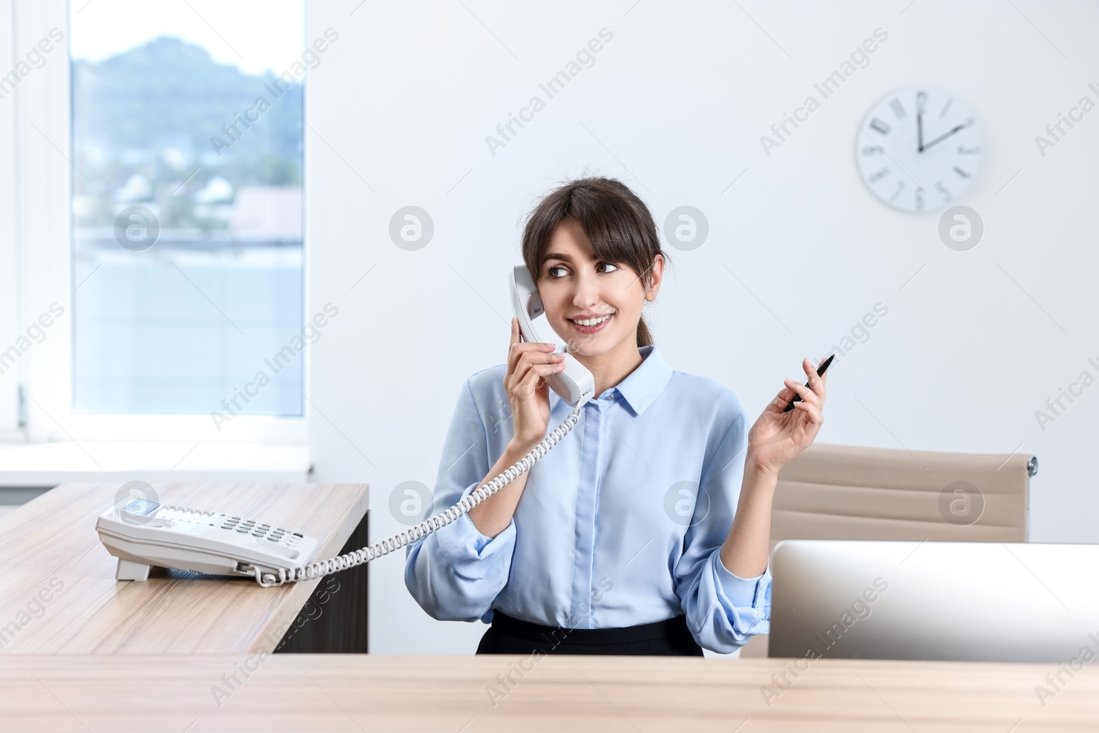 Photo of Professional receptionist talking on phone in office