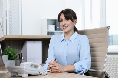 Portrait of receptionist at wooden desk in office