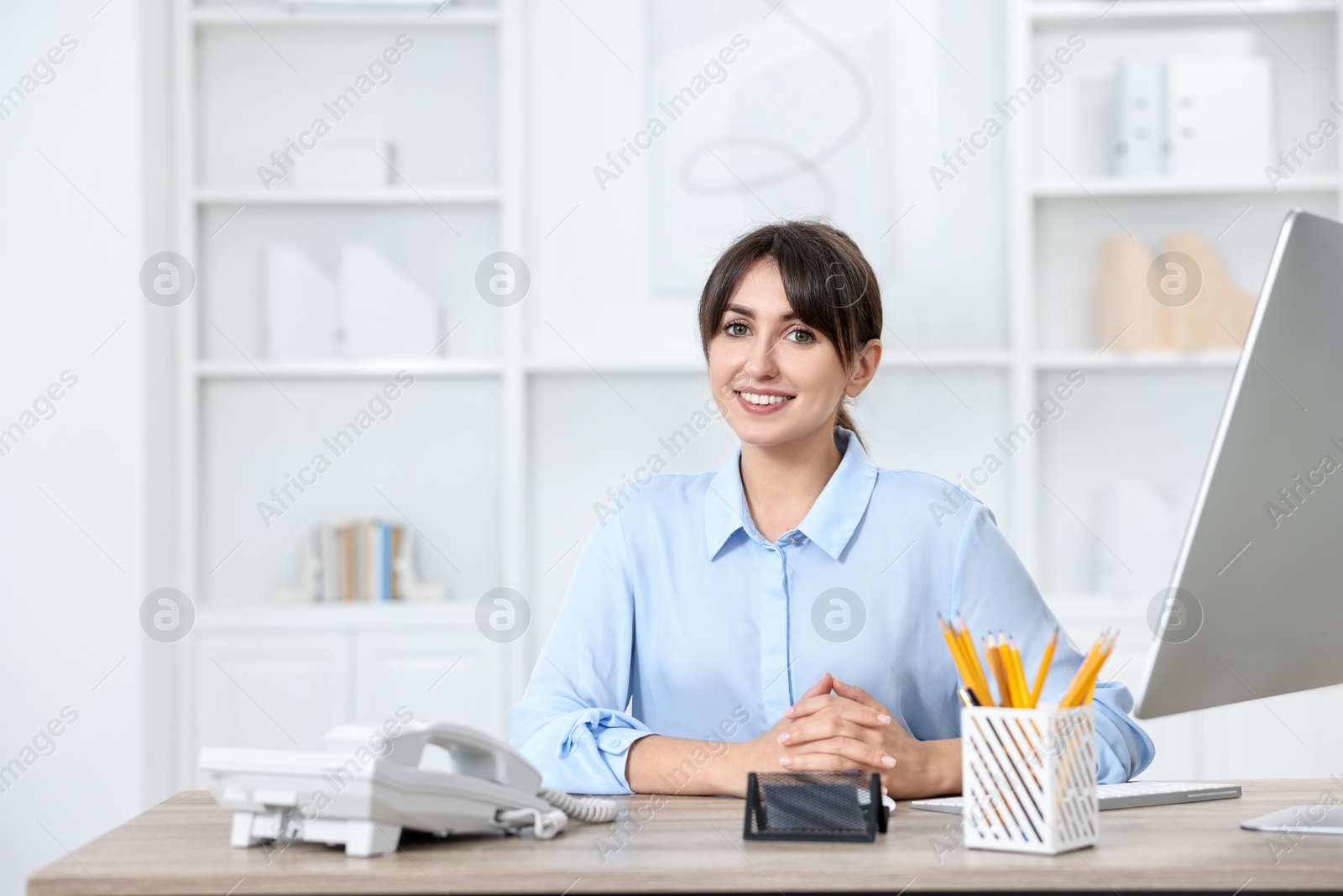 Photo of Portrait of receptionist at wooden desk in office