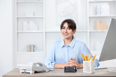 Portrait of receptionist at wooden desk in office