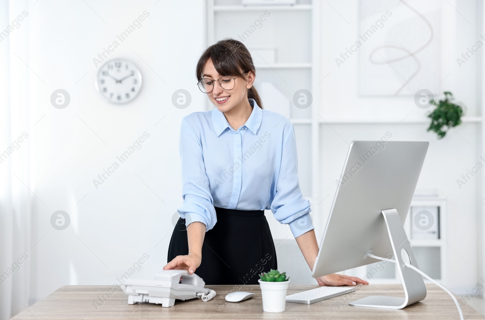 Photo of Professional receptionist working at wooden desk in office