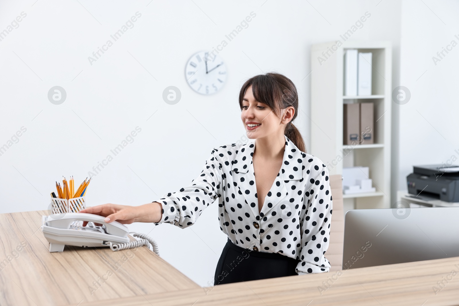 Photo of Professional receptionist working at wooden desk in office