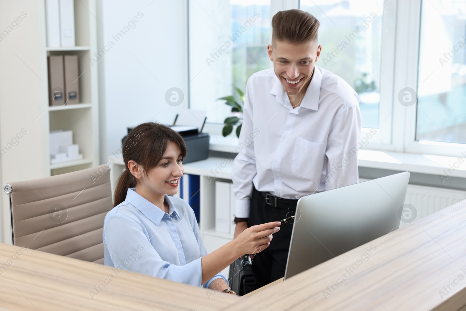 Photo of Professional receptionist working with client in office