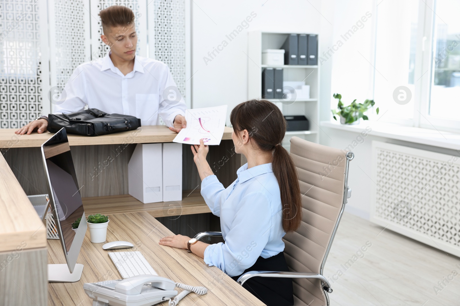 Photo of Professional receptionist working with client in office