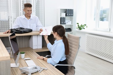 Photo of Professional receptionist working with client in office