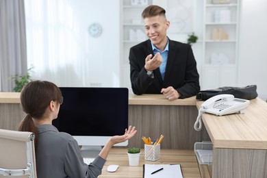 Photo of Professional receptionist working with client in office