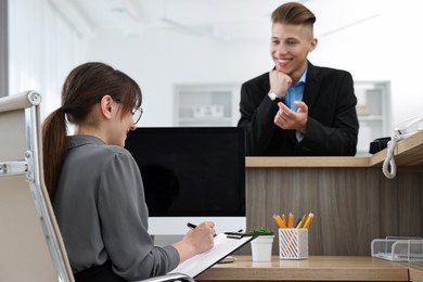 Photo of Professional receptionist working with client in office