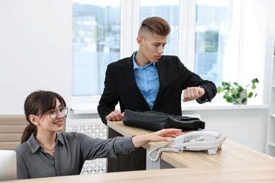 Photo of Professional receptionist working with client in office