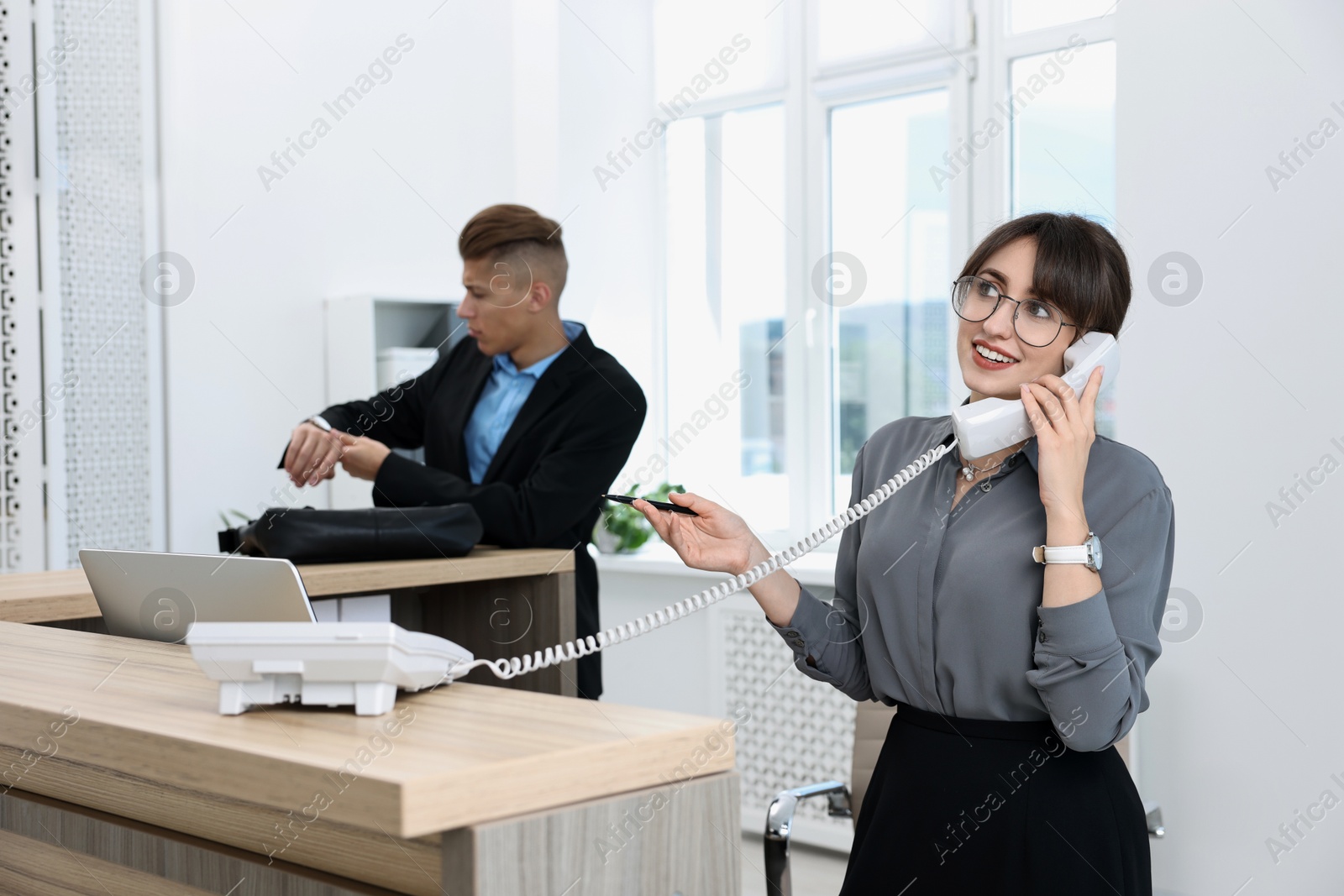 Photo of Professional receptionist working with client in office