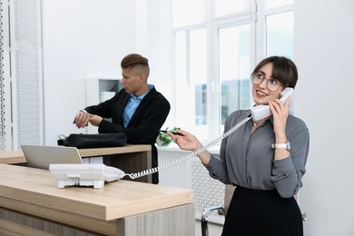 Photo of Professional receptionist working with client in office