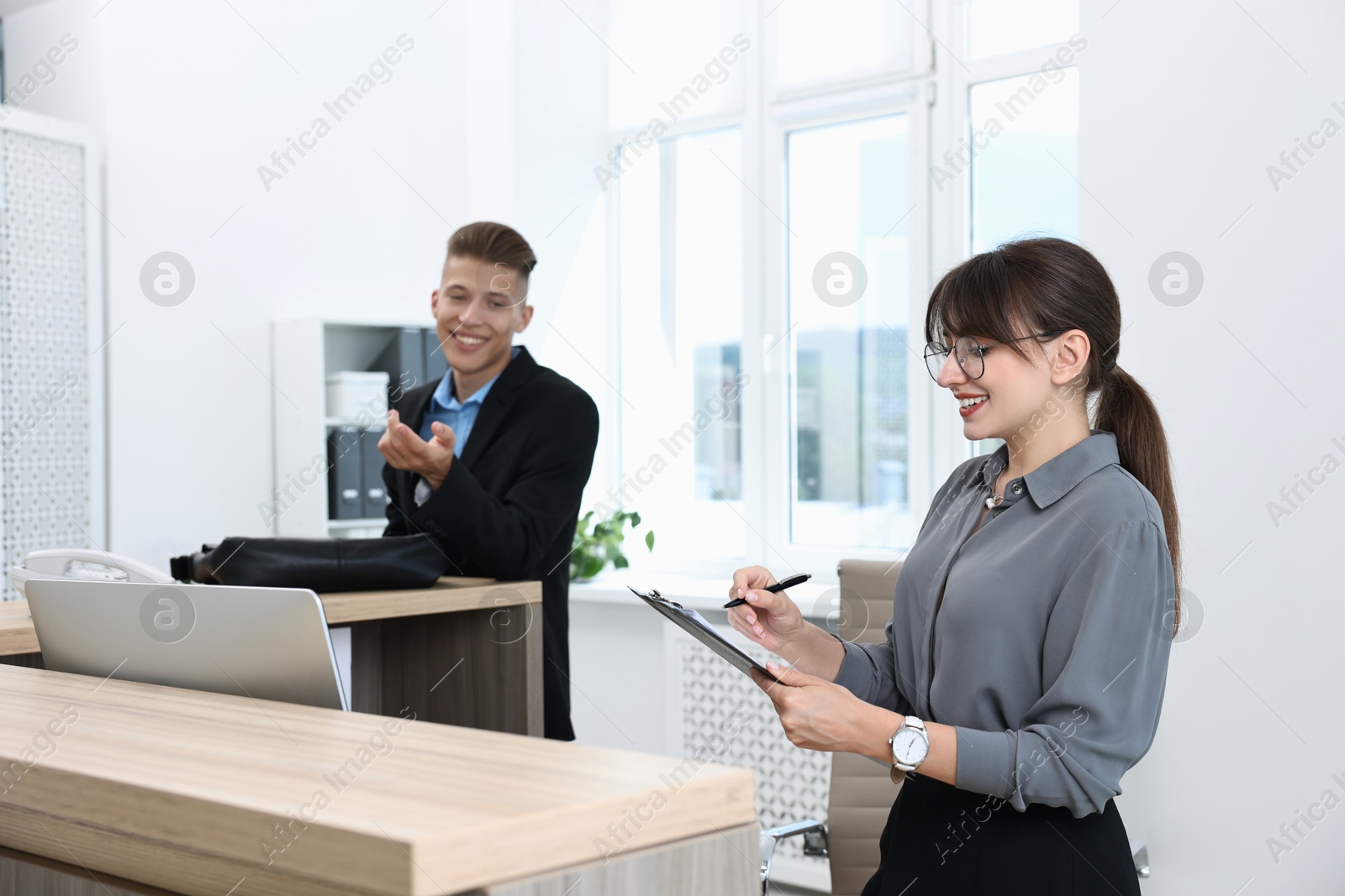 Photo of Professional receptionist working with client in office