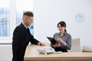 Photo of Professional receptionist working with client in office